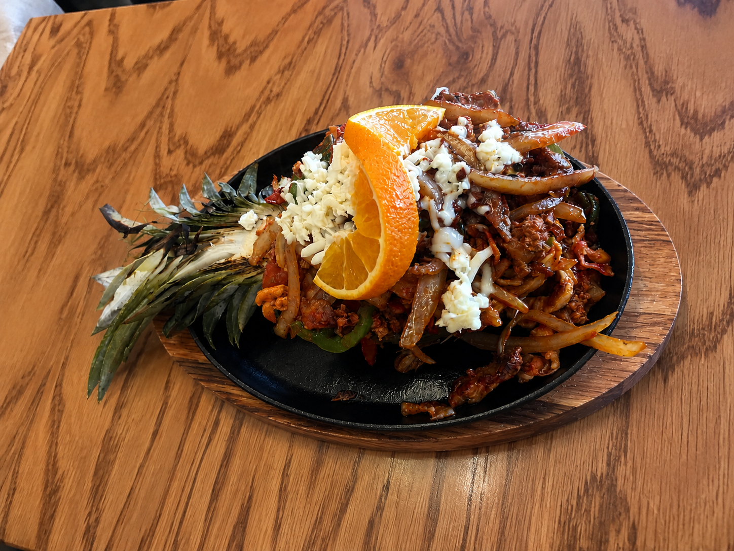 Piña loca sizzling skillet topped with cheese and orange slices